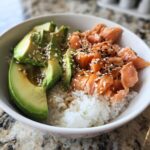 Eine köstliche Avocado Bowl mit Lachs Reis, garniert mit Sesam.