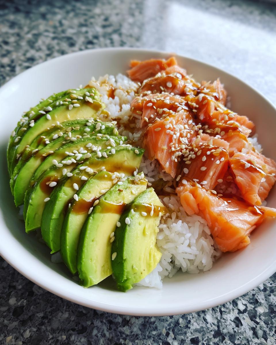 Nahaufnahme einer Avocado Bowl mit Lachs Reis, garniert mit Sesam und Soße.
