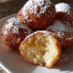 Nahaufnahme von Quarkkeulchen Kartoffeln Zitrone Zucker, bestäubt mit Puderzucker, eines ist aufgebissen.