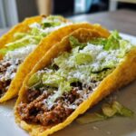Nahaufnahme von zwei Zesty Beef Tacos mit Hackfleisch, Salat und Käse.